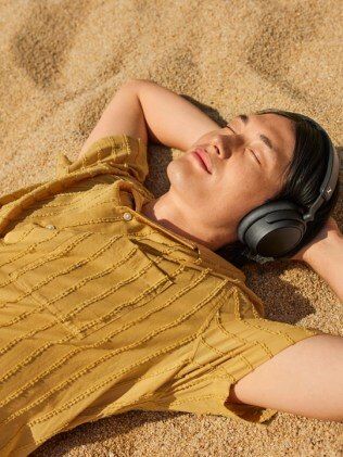 Person hört entspannt Hörbuch am Strand